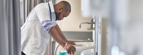 stressed doctor sighing over sink in hospital